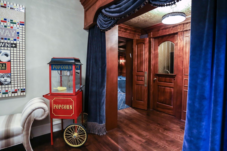 luxury home theater with wooden entry door, blue drapes, and vintage red popcorn machine