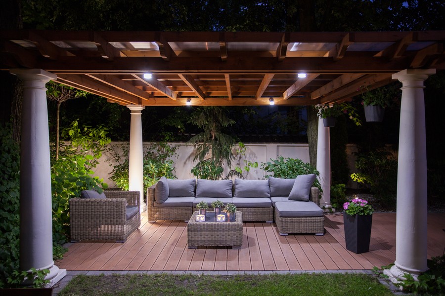 An outdoor pergola at night with the shades rolled completely up.