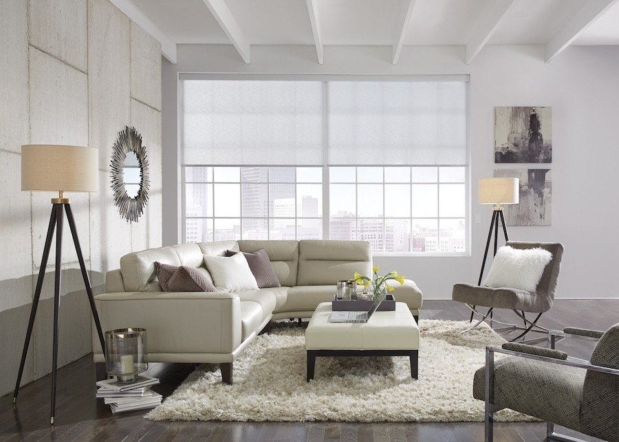 Lutron roller shades partially lowered in a large living room window overlooking a cityscape