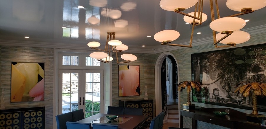 intricate ceiling fixtures illuminating a seating room with large windows in the background