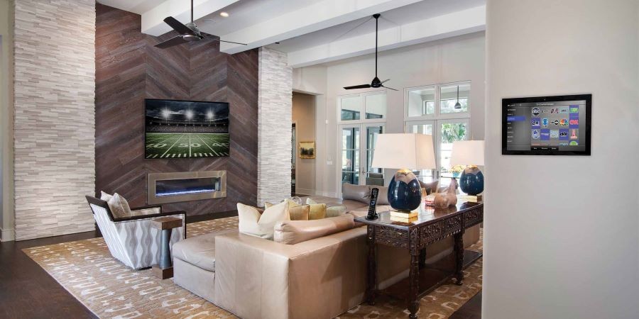 A living room with a TV displaying a football game and a Nice touch panel on the wall. 