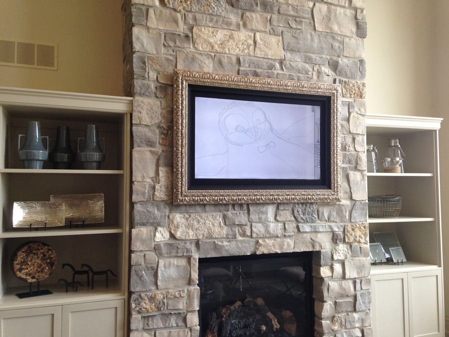 a framed TV installed on a bricked wall over a fireplace