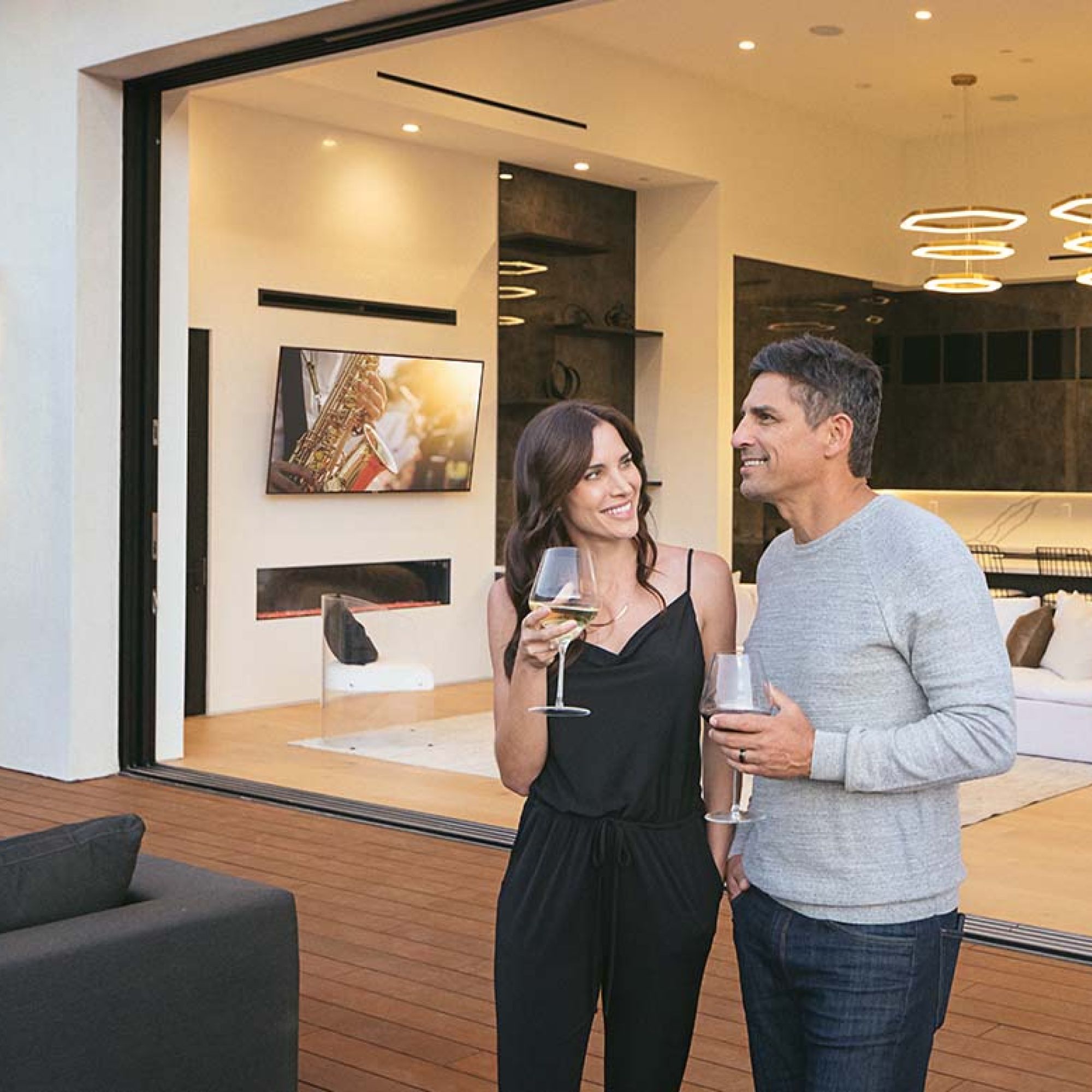 Man and woman drinking wine outside a luxurious and large home